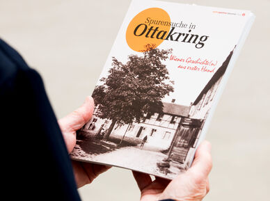 Person hält die wohnpartner-Broschüre "Spurensuche in Ottakring" in den Händen