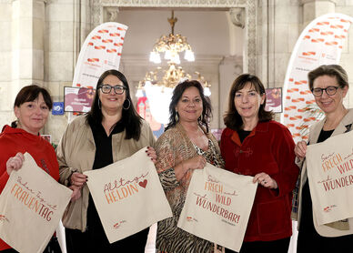 Die fünf Frauen stehen im Wiener Rathaus und halten jeweils eine Stofftasche mit Sprüchen zum Frauentag in Händen.
