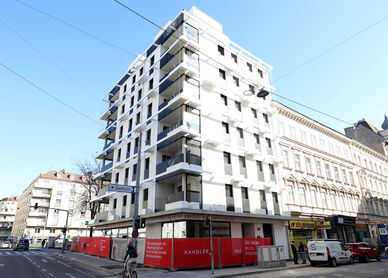 Außenansicht vom Gemeindebau Neu in der Schönbrunnerstraße. Das Foto zeigt eine Ansicht vom 5 mit Bilick in Richtung 6. Bezirk, es sind zwei Seiten des Gebäudes erkennbar, es gibt zahlreiche Balkone