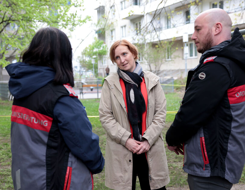 Zwei Ordnungsberater*innen von hinten im Gespräch mit Elke Hanel-Torsch, der Wohnbaustadträtin.