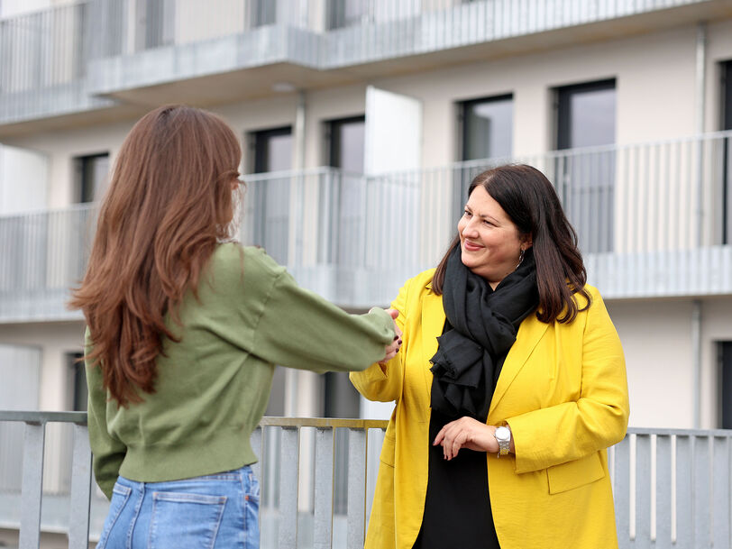 Kathrin Gaál steht einer langhaarigen jungen Frau gegenüber. Die Vizebürgermeisterin schüttelt der Frau die Hand.