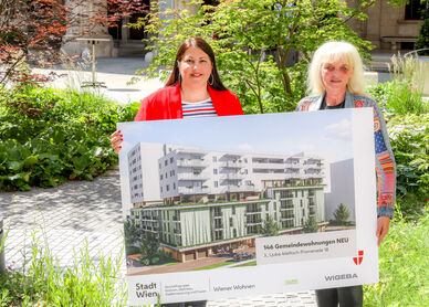 Vizebürgermeisterin Kathrin Gaal hält gemeinsam mit der Bezirksvorsteher-Stellvertreterin des dritten Bezirks, Susanne Wessely eine Tafel, die eine Visualisierung des Gemeindebau NEU im Village im Dritten zeigt.